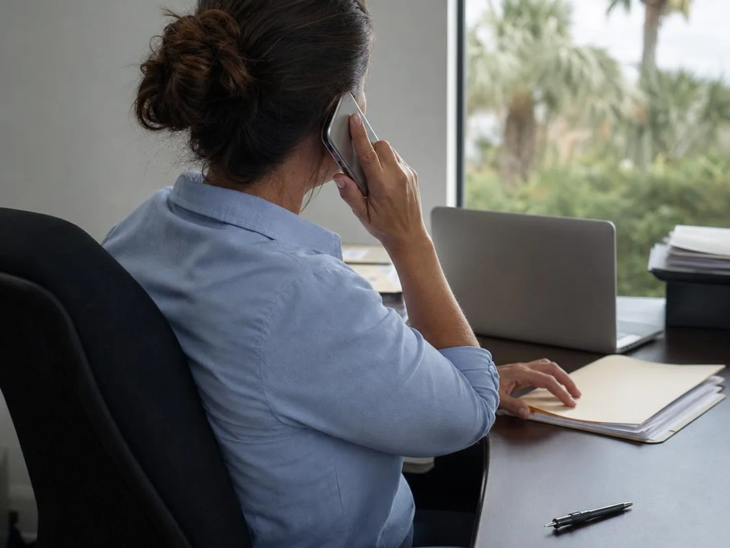 Rear view of a relaxed property manager on the phone about a repair list.